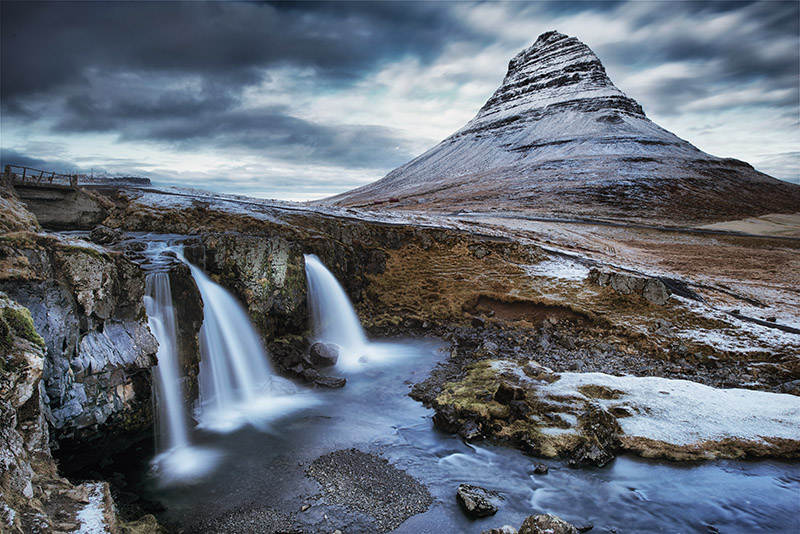 A small waterfall and Kirkjufell mountain in the back